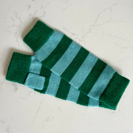 A pair of knit fingerless cashmere gloves with alternating dark green and light blue-green horizontal stripes, displayed on a light marble surface.