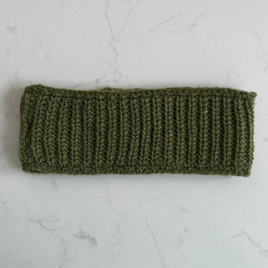Khaki green plain knitted woollen headband with fleece lining on a light gray marble background